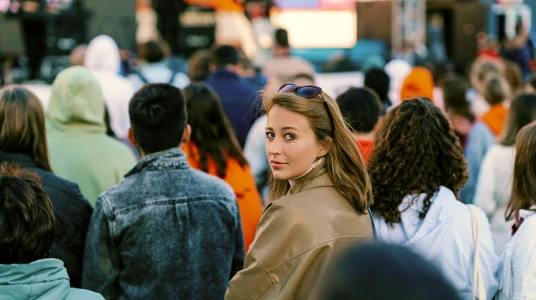 Young woman looking back among a crowd attending an outdoor event or concert.