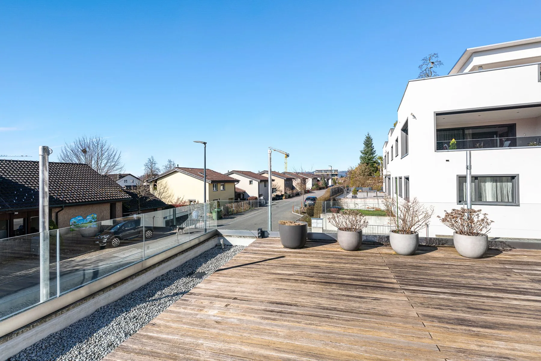 Holzterrasse mit Glasgeländer und Pflanzkübeln am Einfamilienhaus in Affoltern am Albis