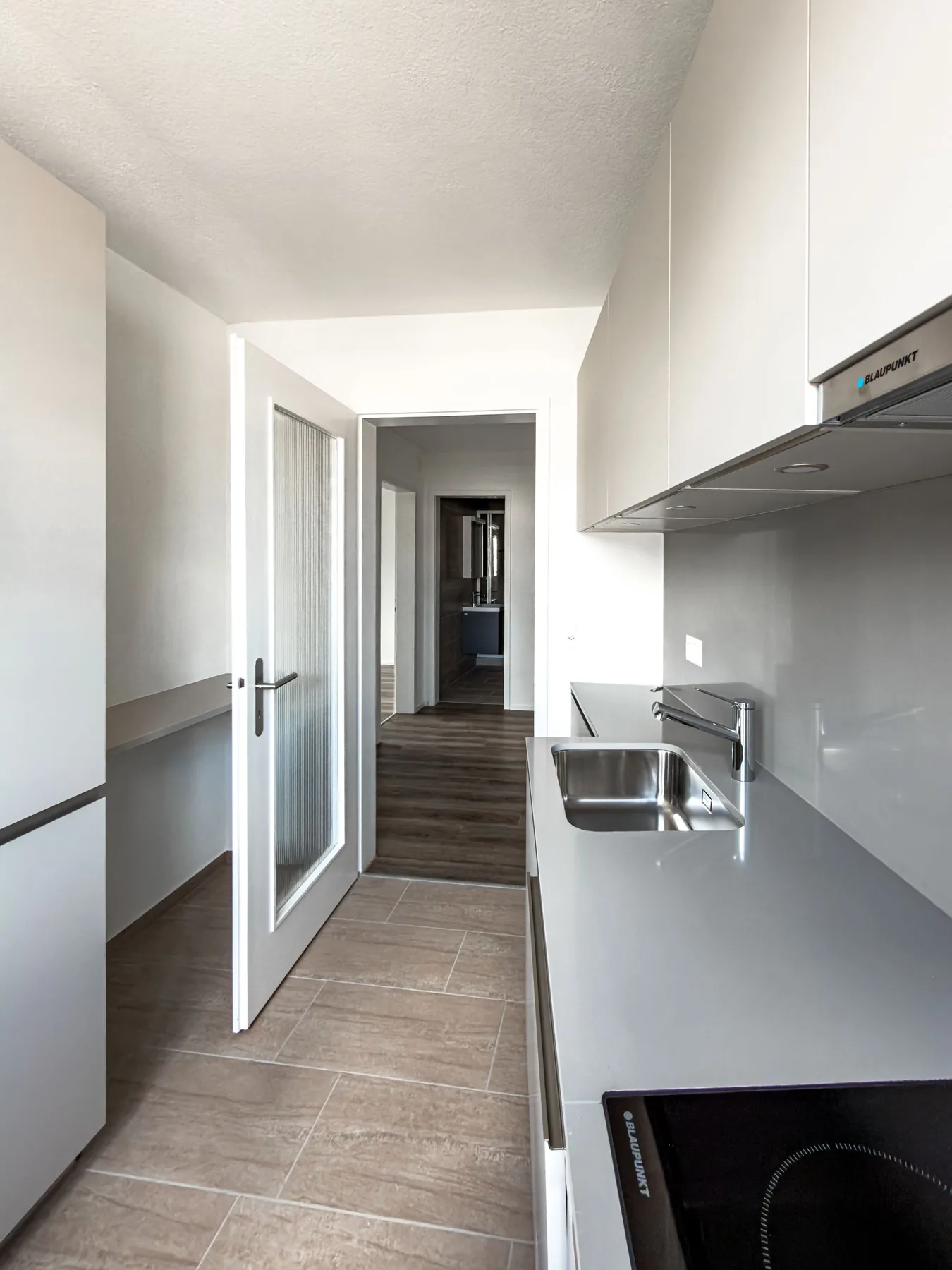 Schmale Küche mit Spüle, Kochfeld und Arbeitsfläche in der Maisonette an der Witikonerstrasse 423