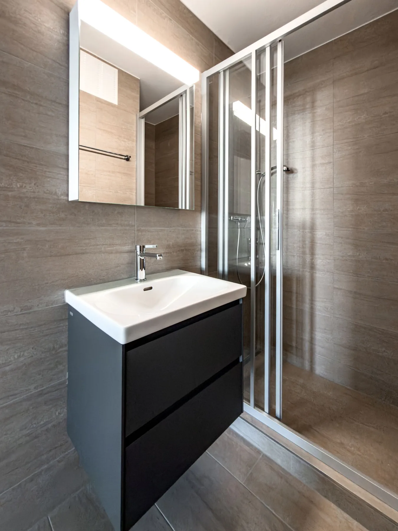 Badezimmer mit Waschtisch, Spiegel und verglaster Dusche in der Maisonette an der Witikonerstrasse 423