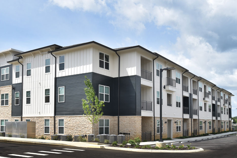 Three-story Lakemoor Station Apartments with white and charcoal siding, stone base and balconies