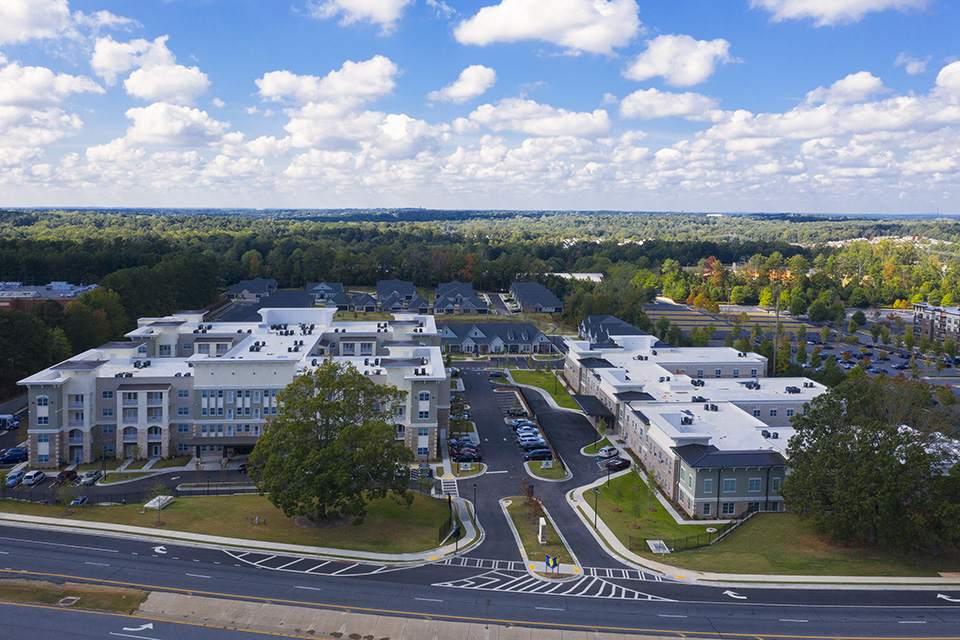 Aerial view of The Mansions at Gwinnett Park apartment buildings surrounded by trees