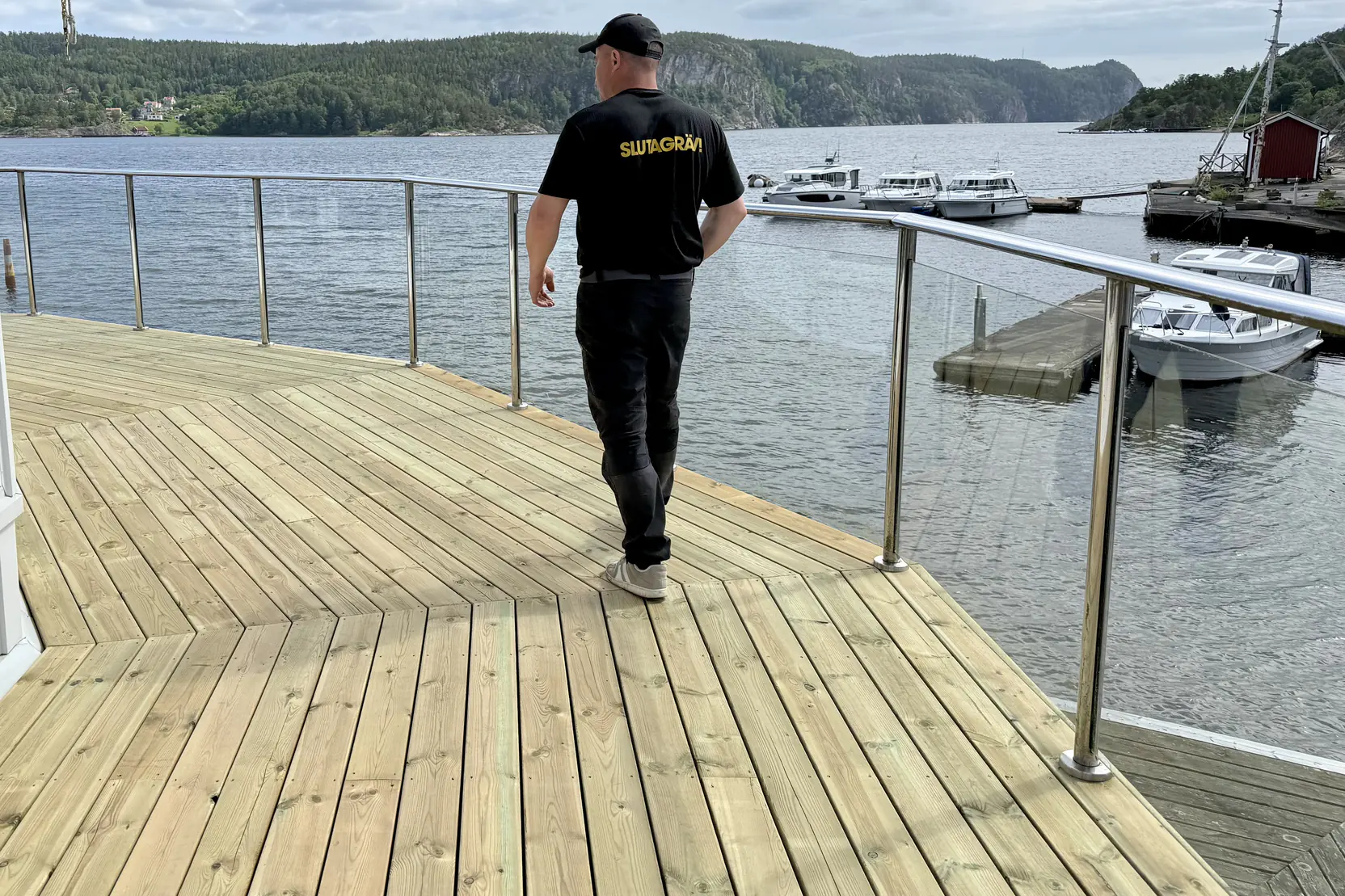 Nybyggt trädäck med glasräcke ut mot vattnet utanför Uddevalla