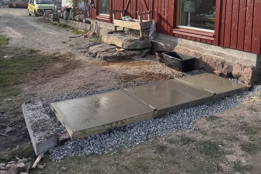 Nygjuten betongplatta framför entrén till ett rött hus