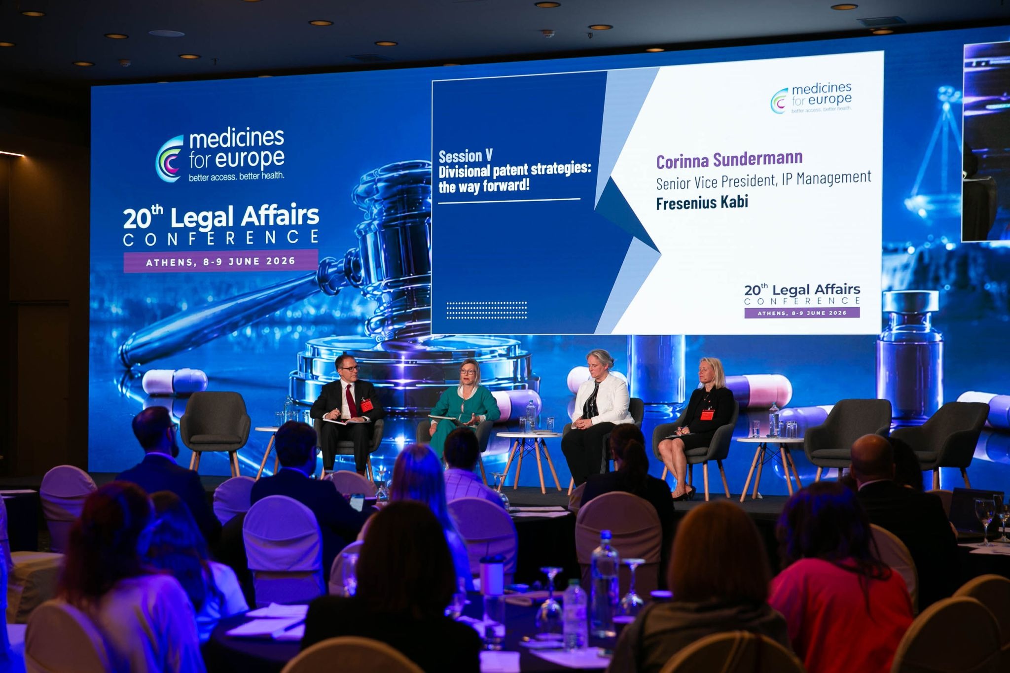 Conference panel on stage at the Legal Affairs Conference discussing divisional patent strategies, with speaker name and title displayed on a large screen