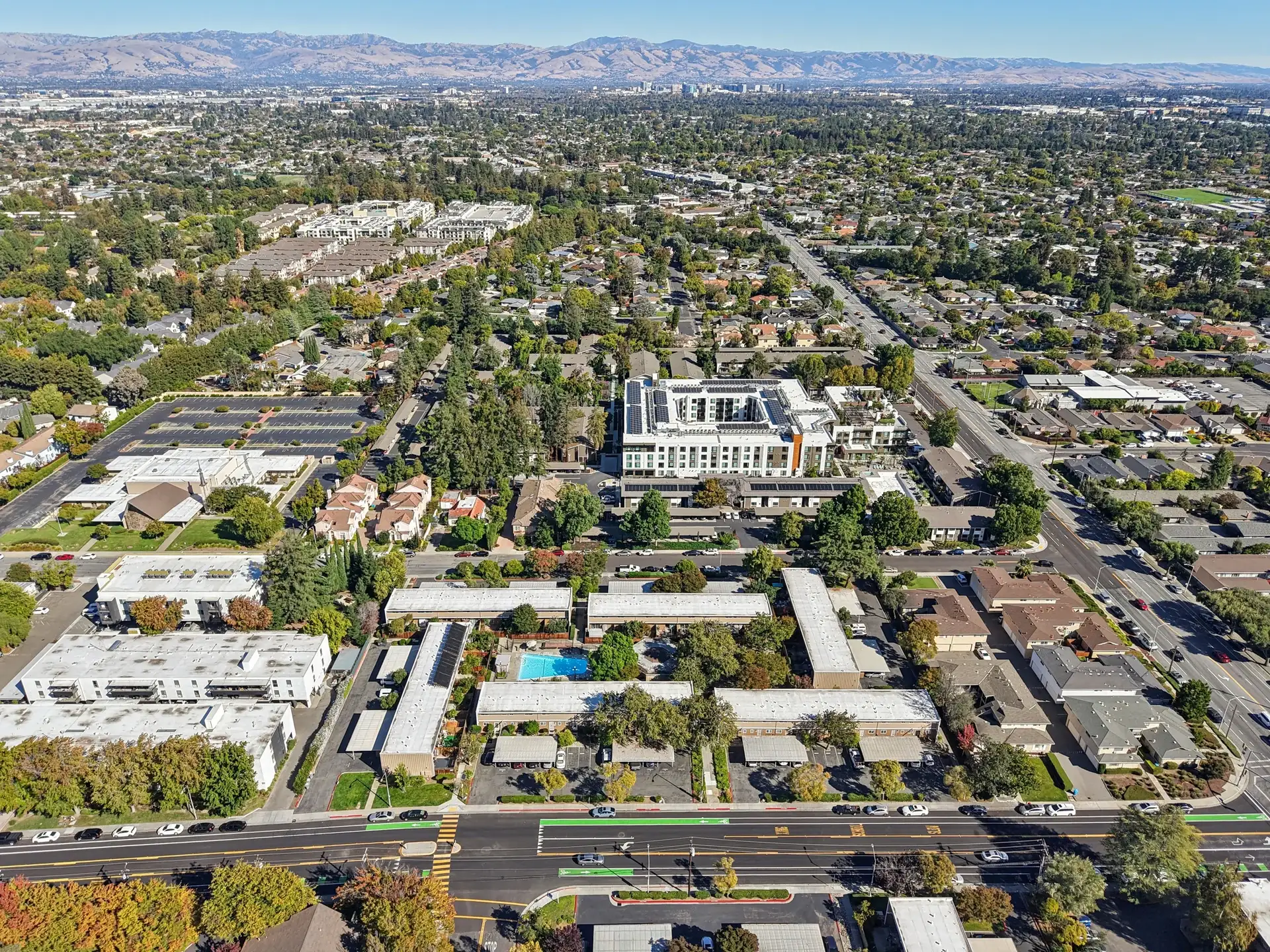 Aerial view of Santa Clara, California, tree-lined residential streets and low apartment blocks across the flat valley with the Diablo Range on the horizon