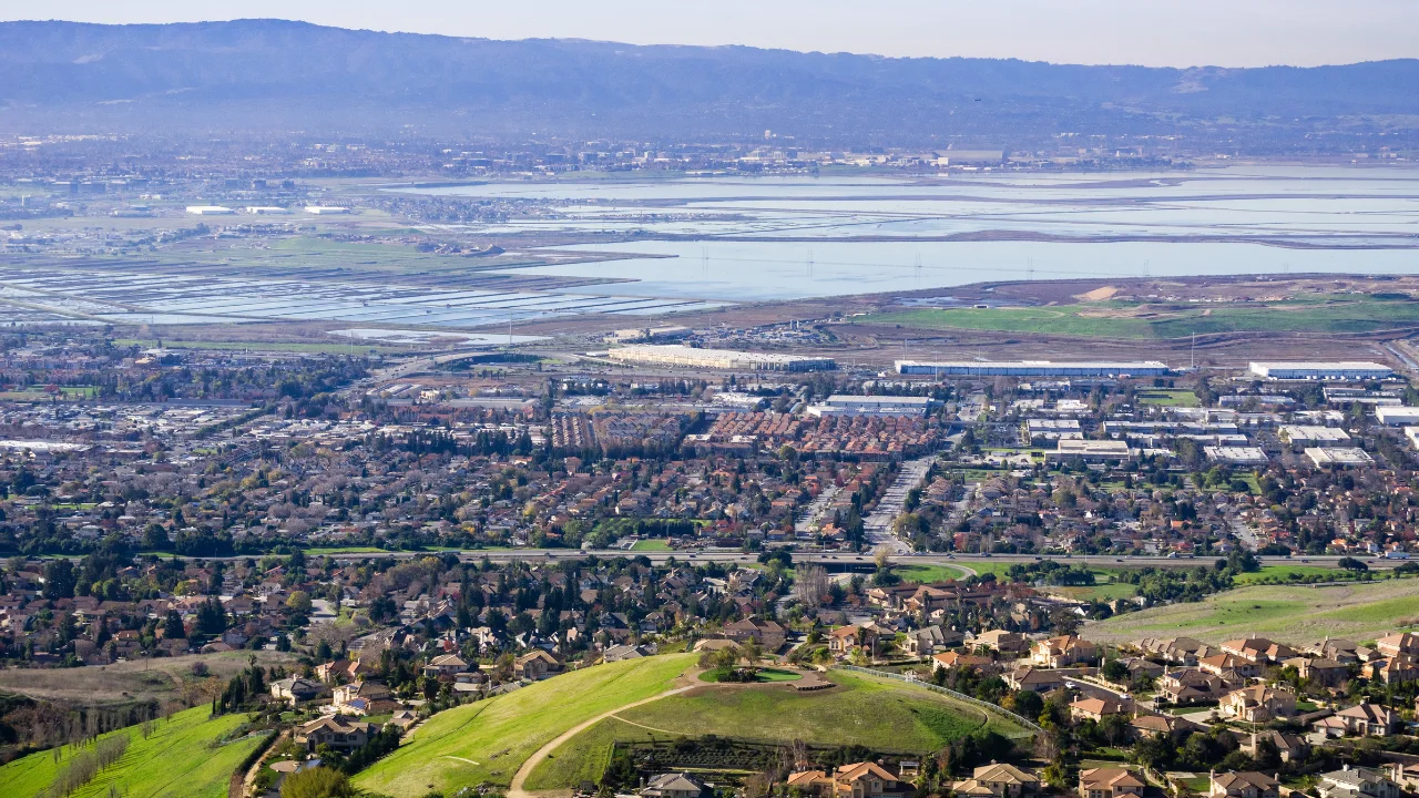 View west over Milpitas, California from the eastern hills, residential neighbourhoods below green slopes with the South Bay salt ponds beyond