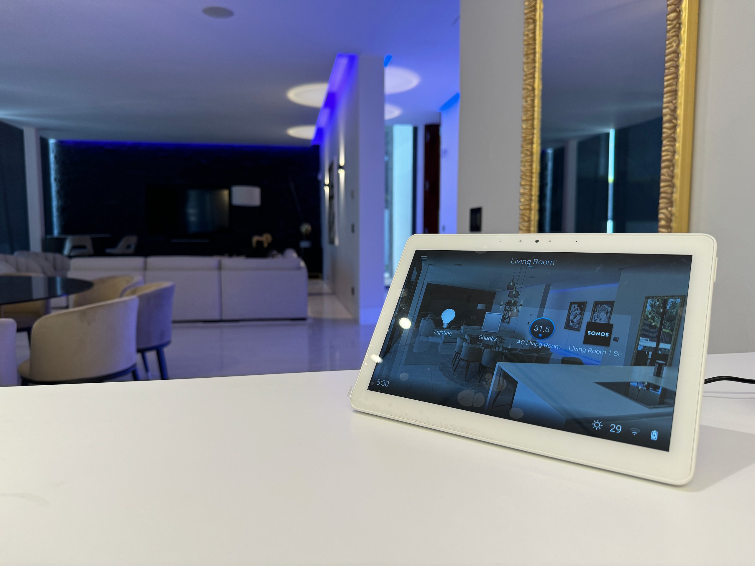 Touchscreen home controls in a living room with blue accent lighting