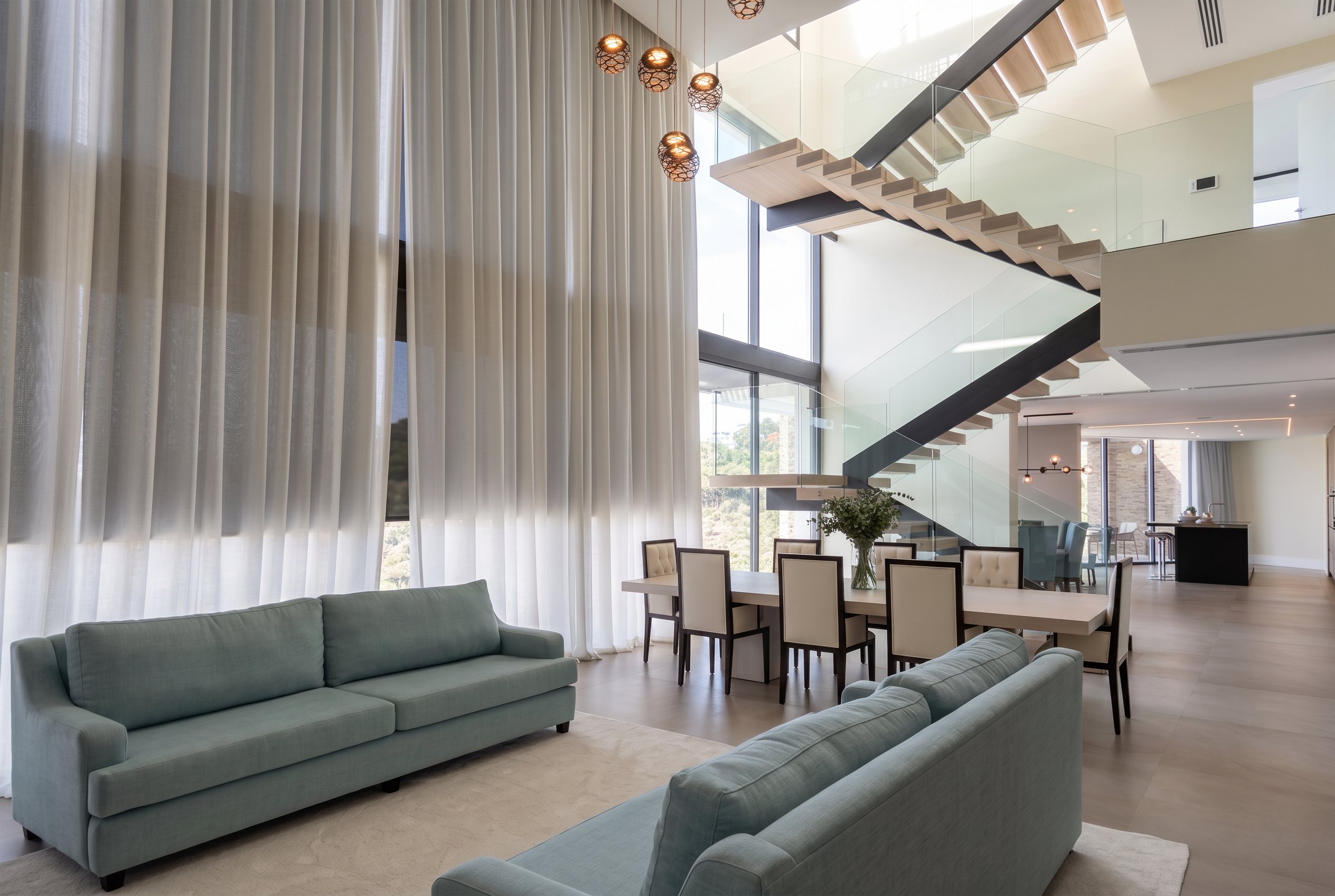 Double-height living room with curtains and a floating staircase