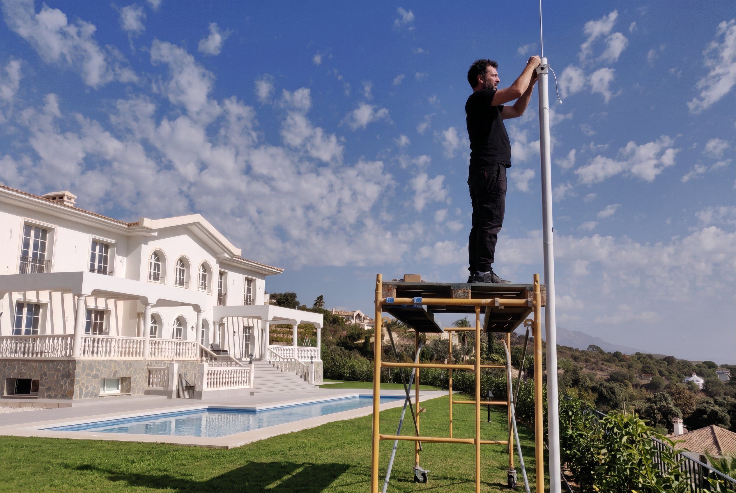 UNCOM technician installing exterior equipment at a villa