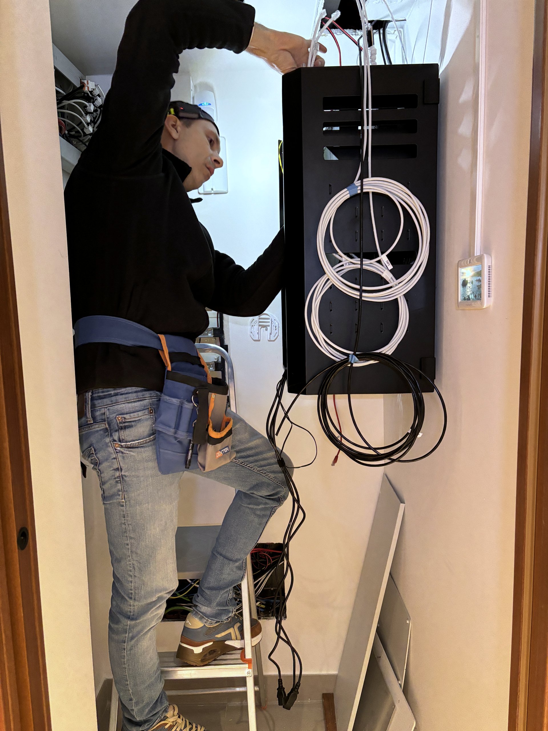 UNCOM technician installing cabling in a residential network cabinet