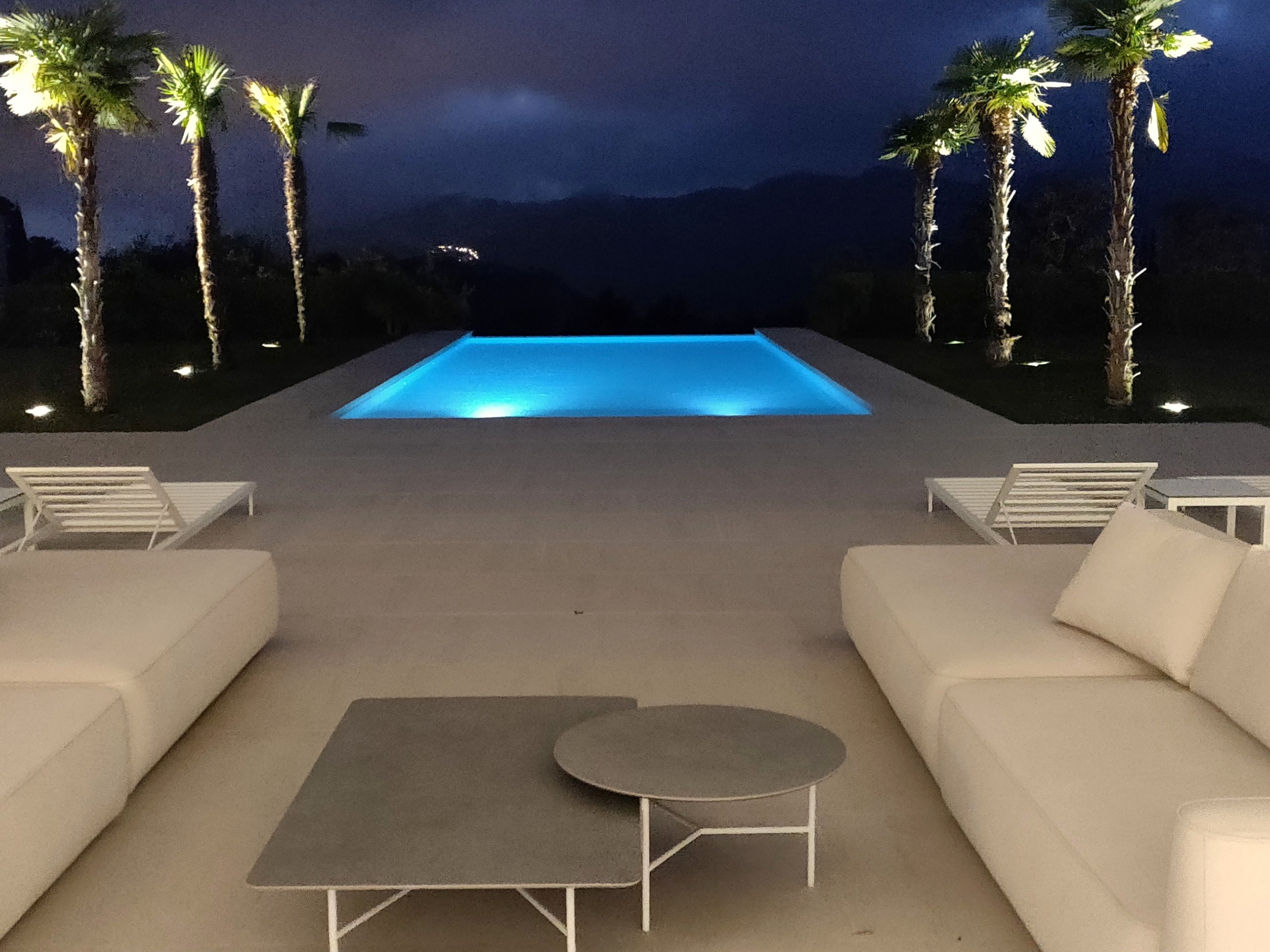 Pool terrace and palm trees illuminated by an exterior lighting system