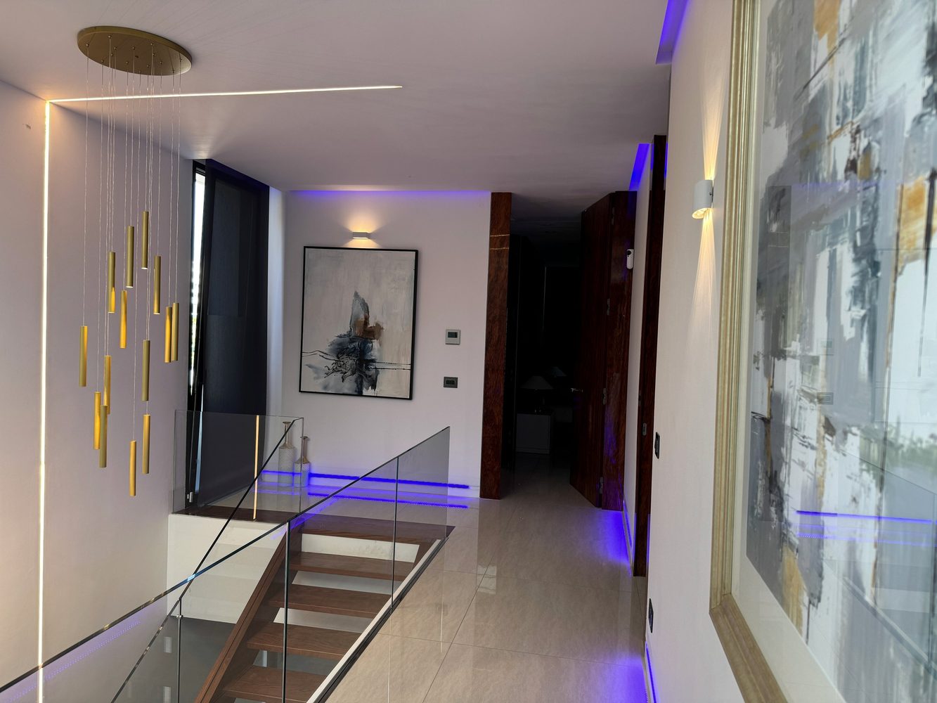 Double-height hall with chandelier, wall lights and linear lighting