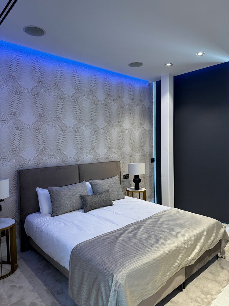 Modern villa bedroom with blue cove lighting and ceiling speakers