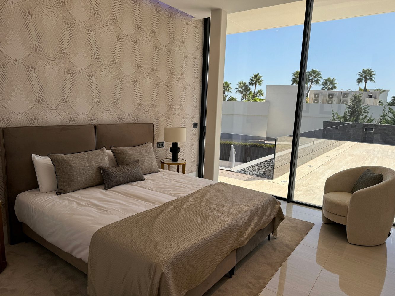 Modern villa bedroom with full-height glazing and terrace view