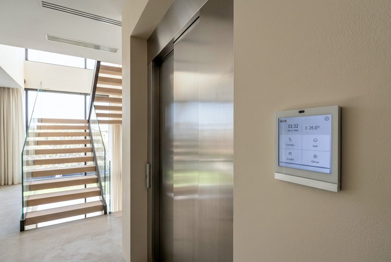 Smart-home touchscreen beside the lift and staircase in a private villa