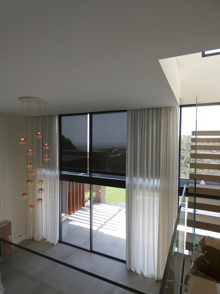 Automated curtains and pendant lighting beside double-height glazing