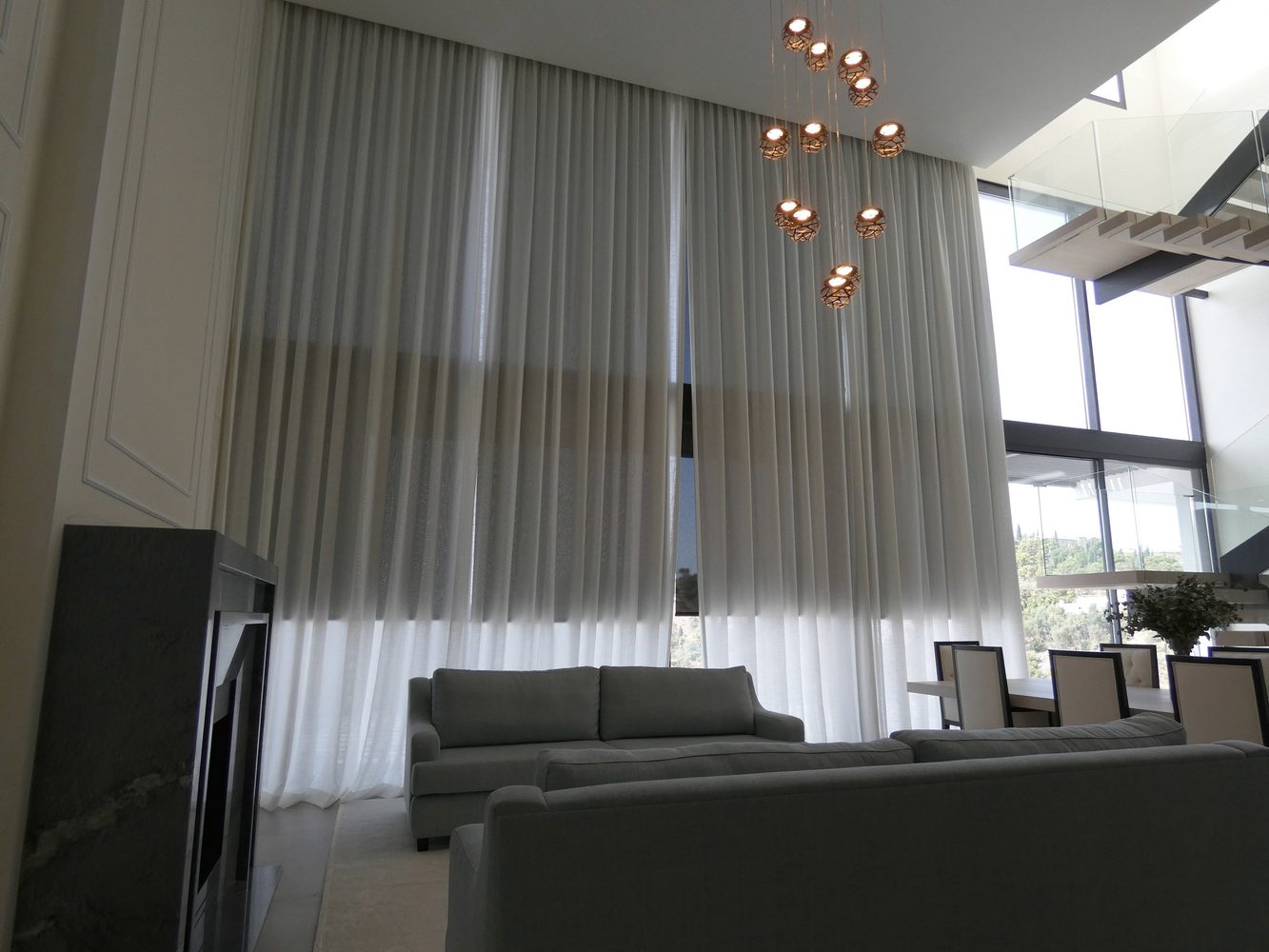Living room with full-height automated curtains and pendant lighting