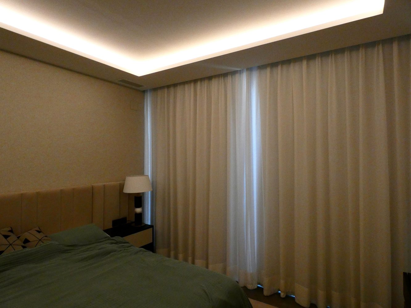 Bedroom with warm cove lighting and floor-to-ceiling curtains