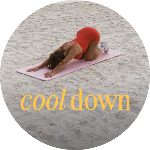 Woman in red workout outfit stretching on a mat on sand, text says 'cool down'.