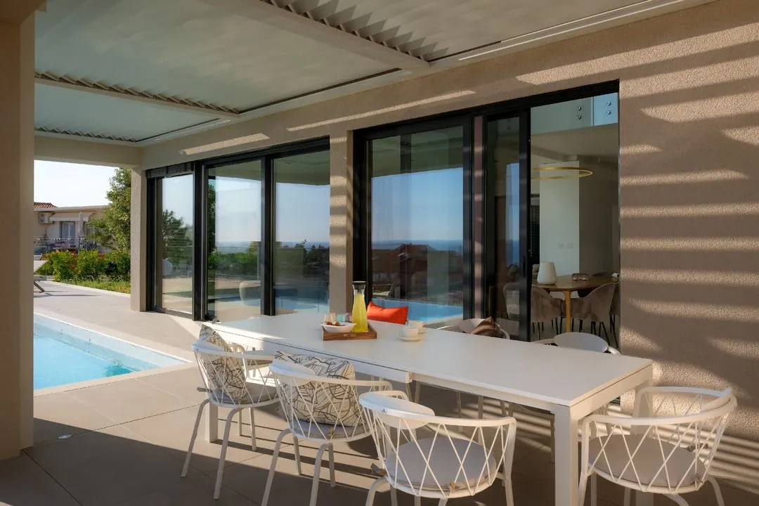 Covered terrace with a long dining table beside the pool