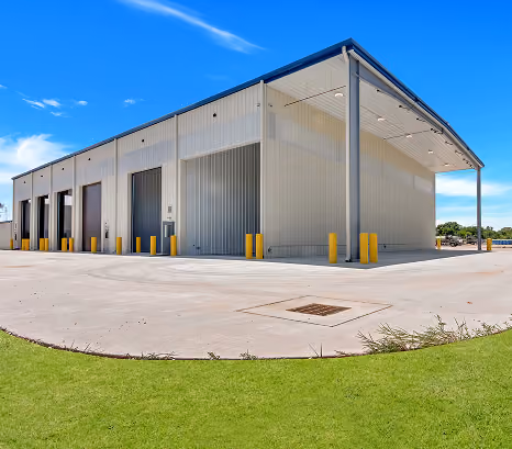 Exterior of a hauling maintenance building with tall open bays and yellow bollards