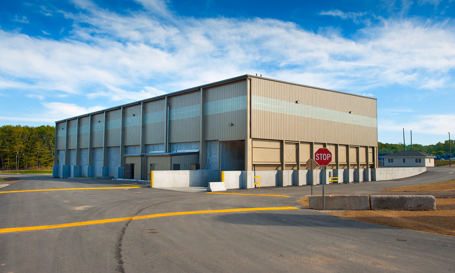 Exterior of a transfer station with a glazed upper wall and a stop sign at the exit drive