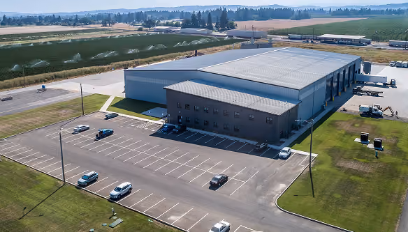 Aerial view of a material recovery facility with parking and open farmland behind