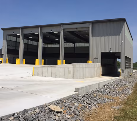 Exterior of a dark metal facility with open tipping bays above a concrete wall
