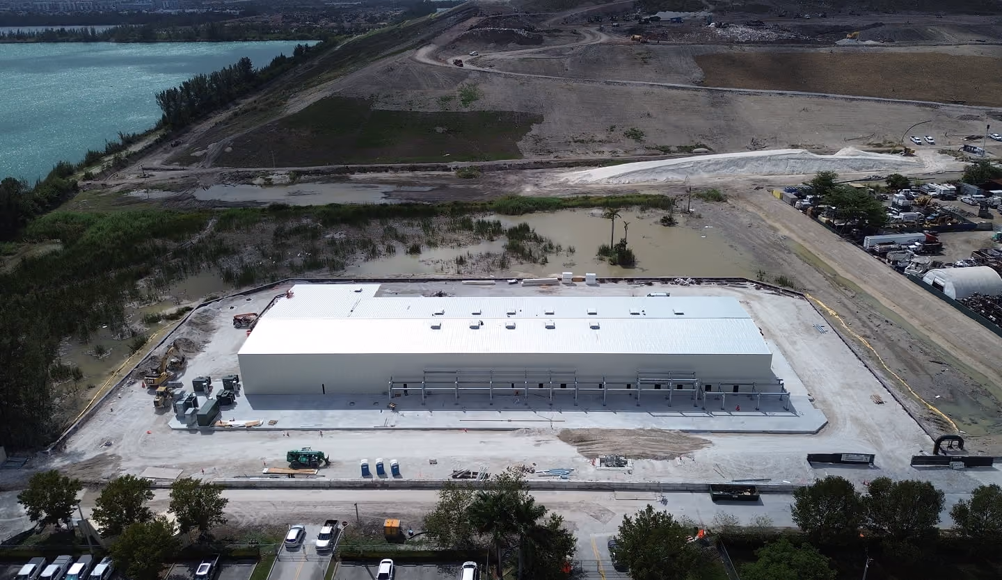 Aerial view of a white processing building on a graded industrial site