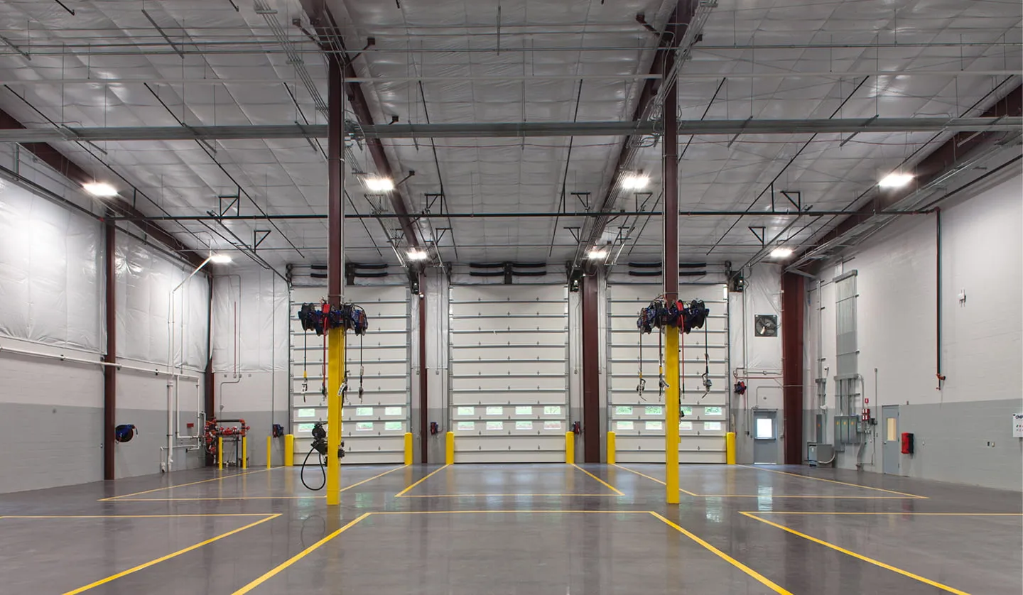 Interior of a completed maintenance building with overhead doors and painted floor lanes