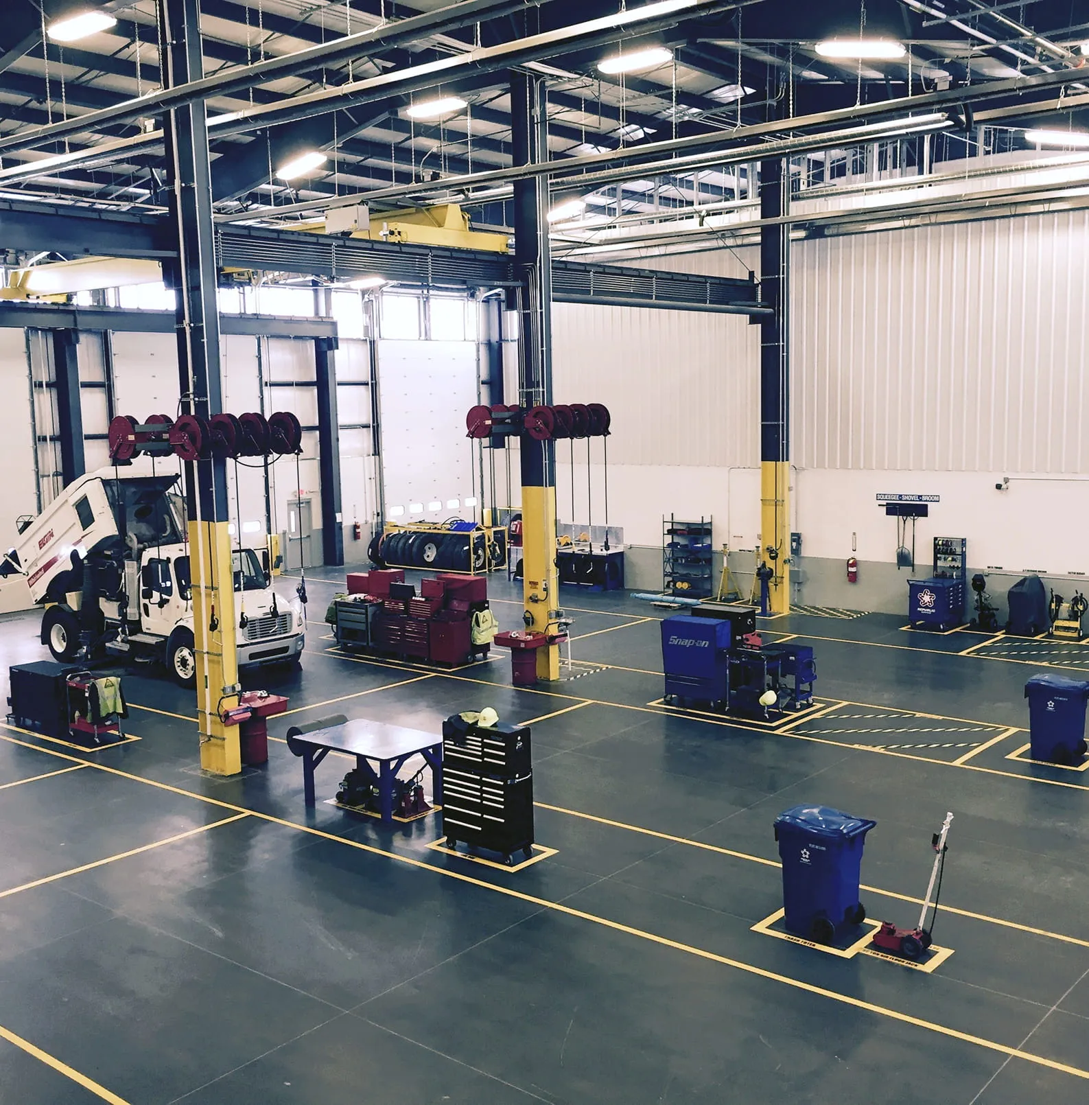 Interior of a truck maintenance shop with vehicle lifts and marked service bays