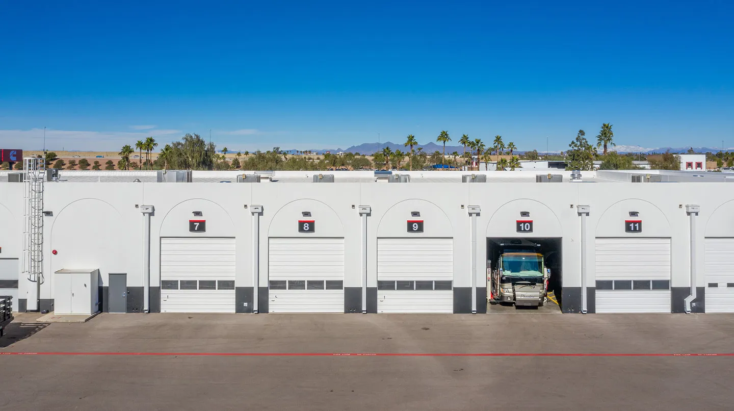 Exterior of a long white maintenance facility with numbered overhead doors