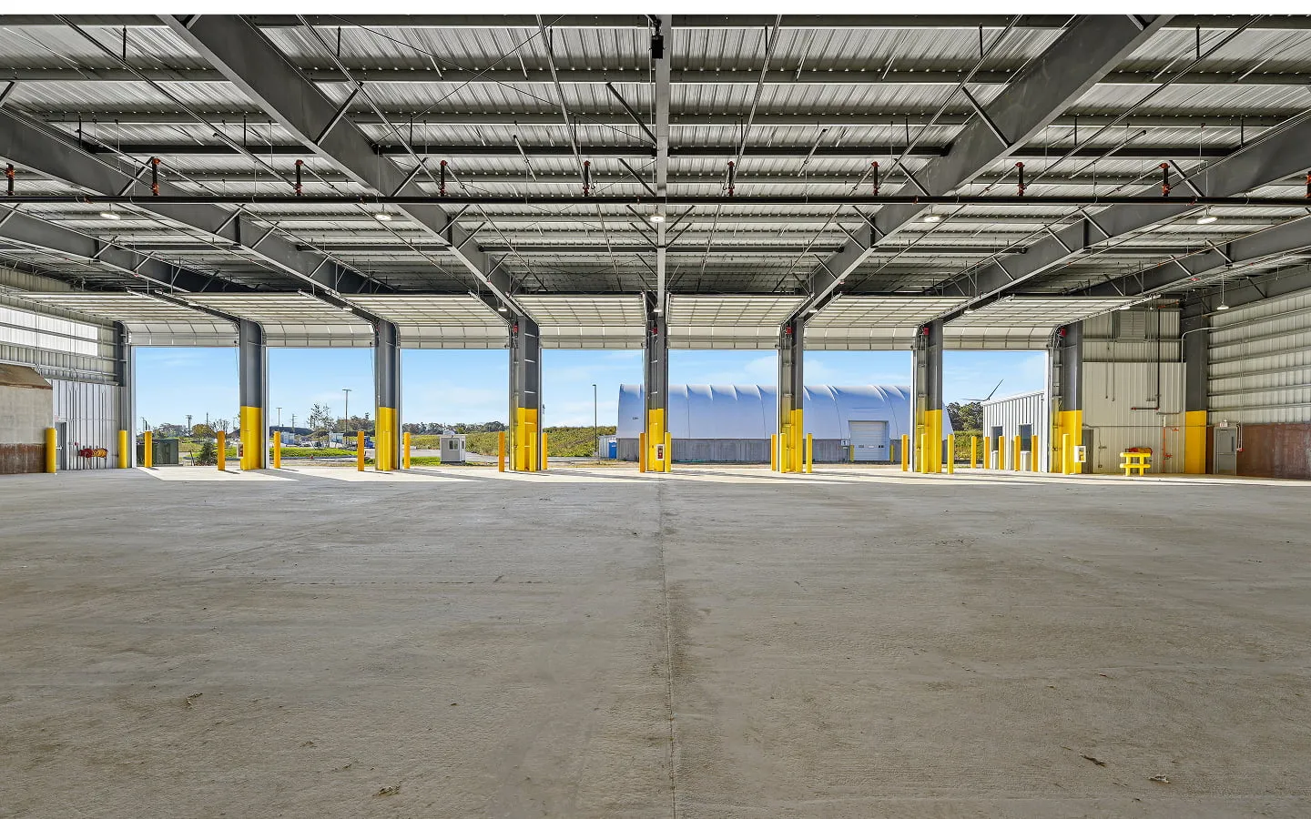 Interior of a completed maintenance building with open overhead doors and yellow bollards