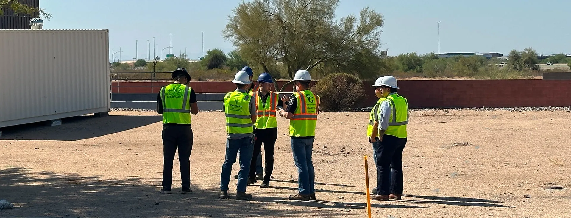Small group of workers in hi-vis vests walking a graded job site