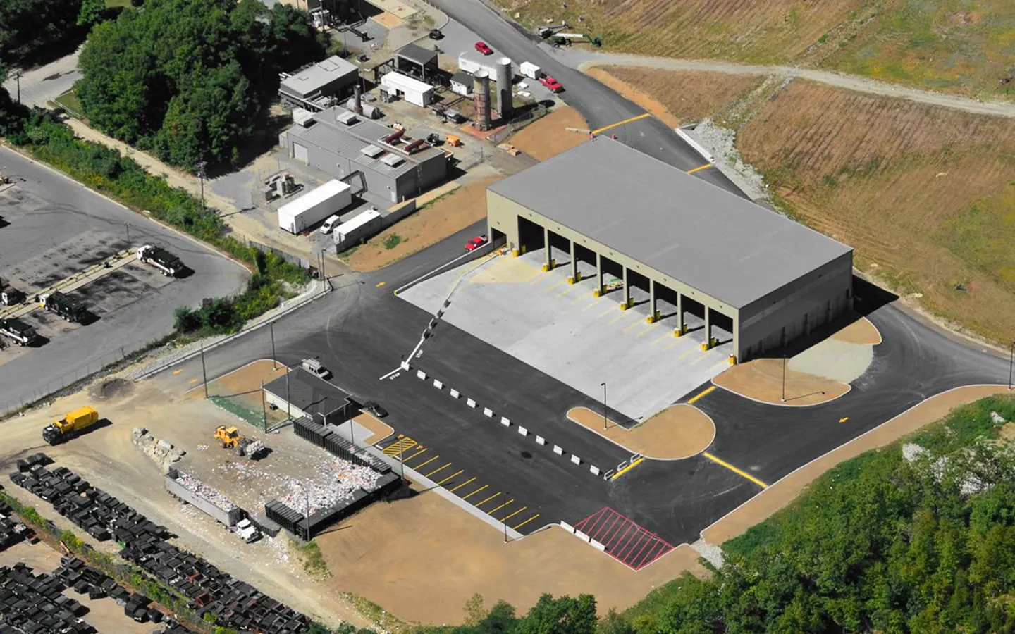 Aerial view of a transfer station with a covered tipping area and truck scale drive