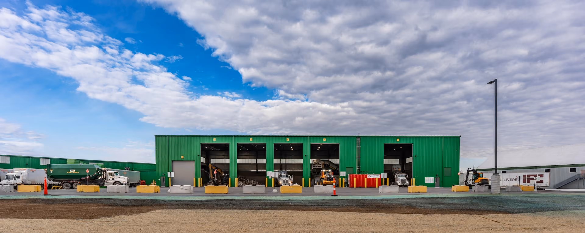 Exterior of a green-clad material recovery facility with a row of tipping bays