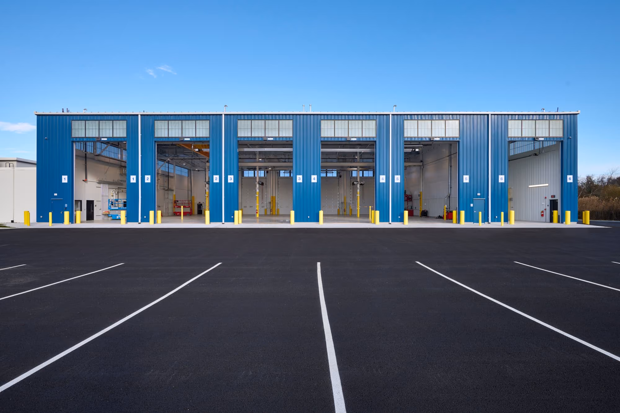 Exterior of the New Bedford transfer station with blue overhead doors and a freshly paved apron