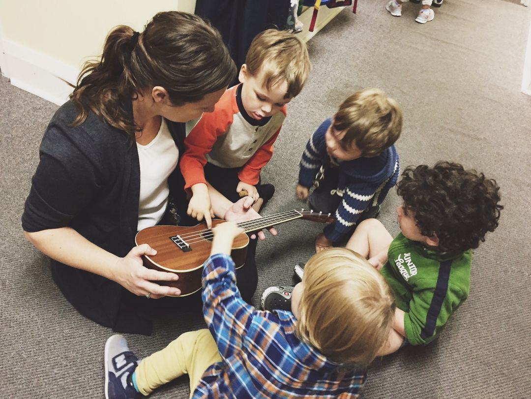 Senior preschoolers singing with a ukulele at group time