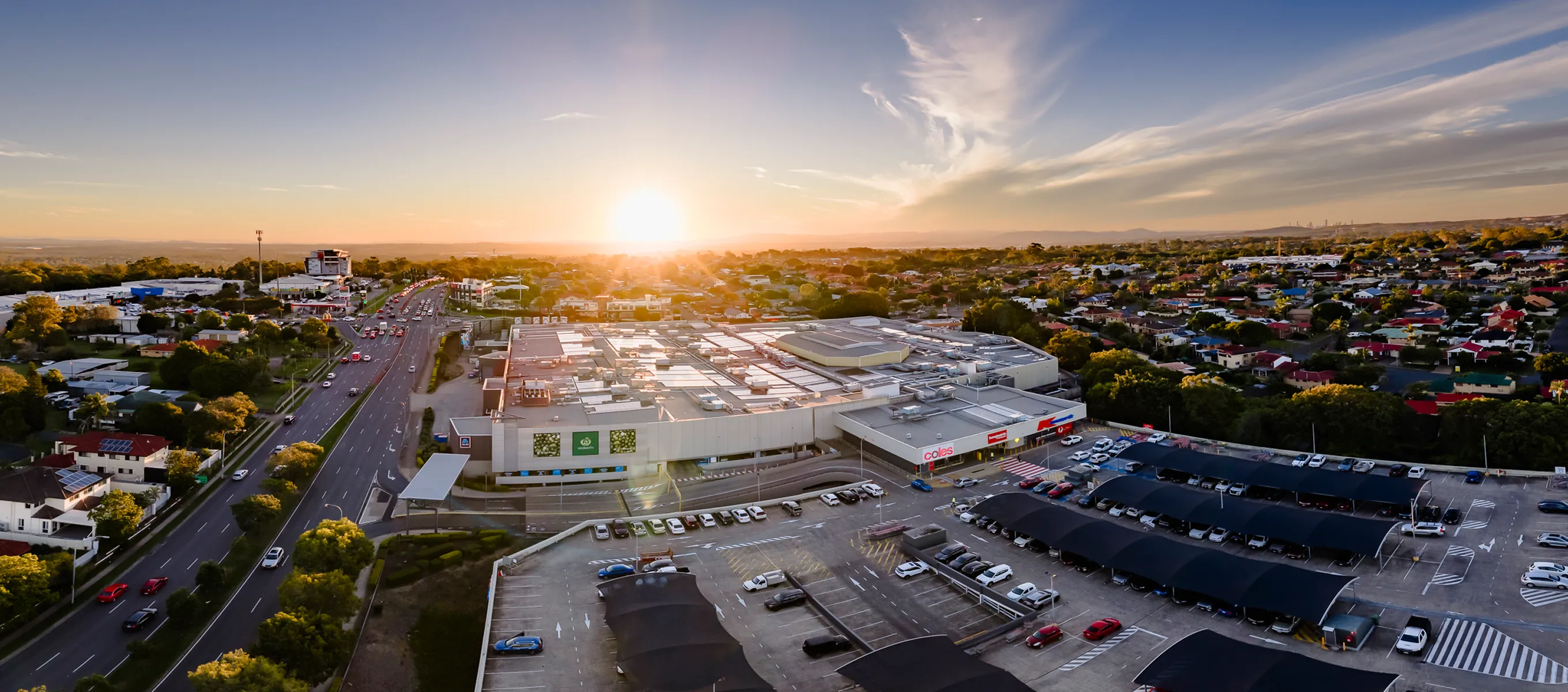 Aerial view of Sunnybank Hills Shoppingtown complex and surrounding residential suburb at sunset.