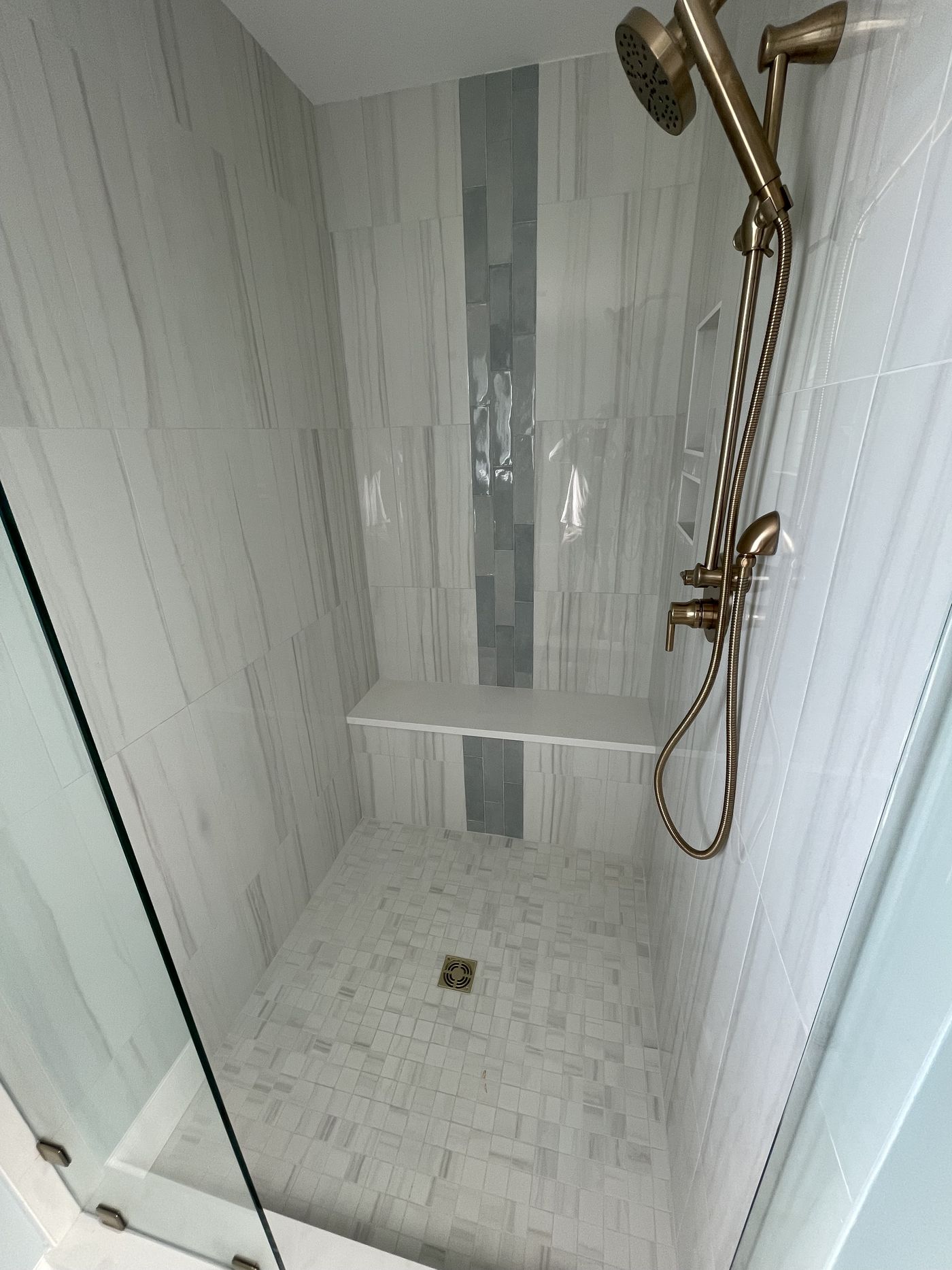 Walk-in tile shower with brass fixtures and built-in bench — Daybreak Construction
