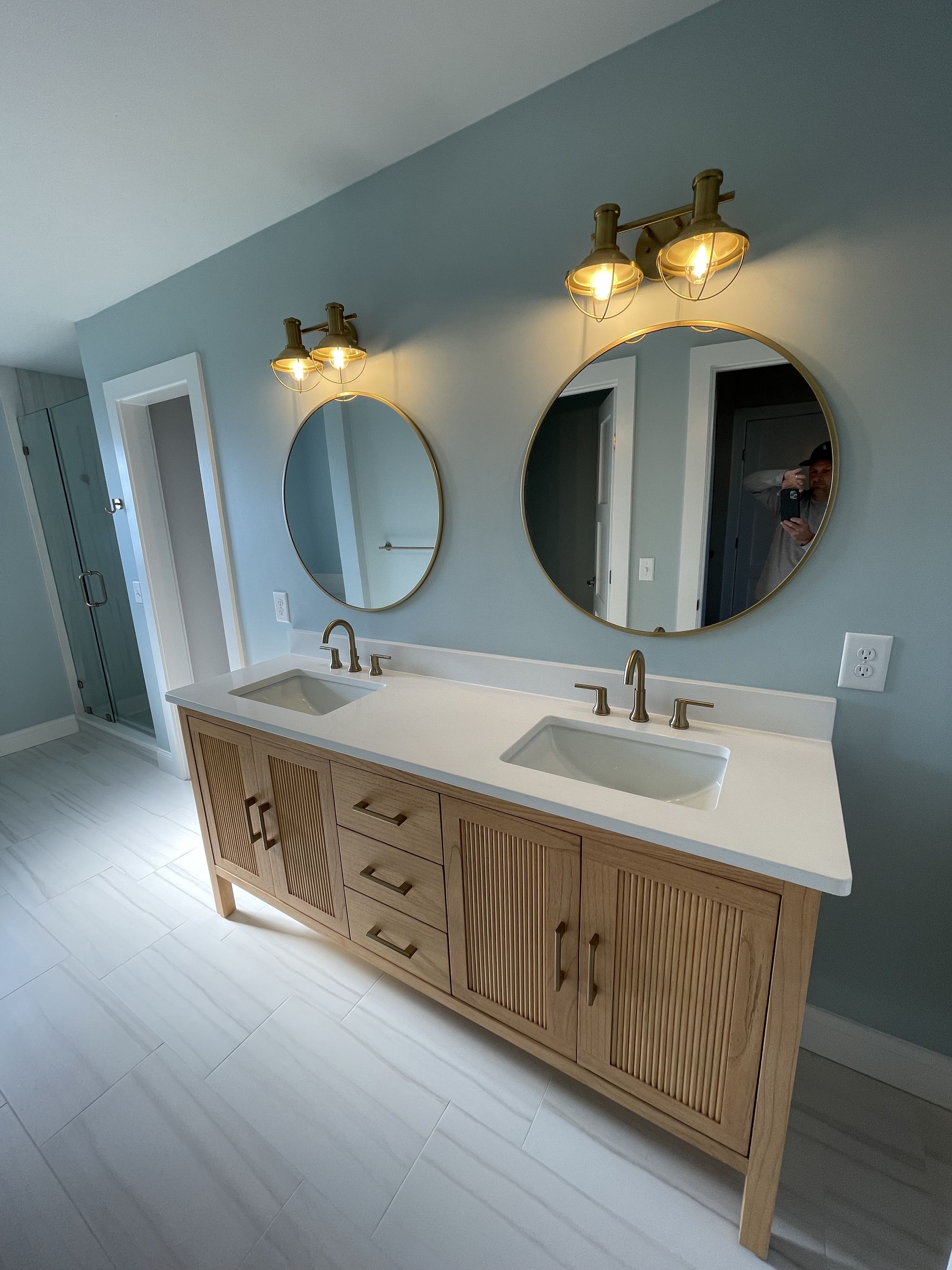Bathroom remodel with double vanity, round mirrors, and brass lighting — Daybreak Construction