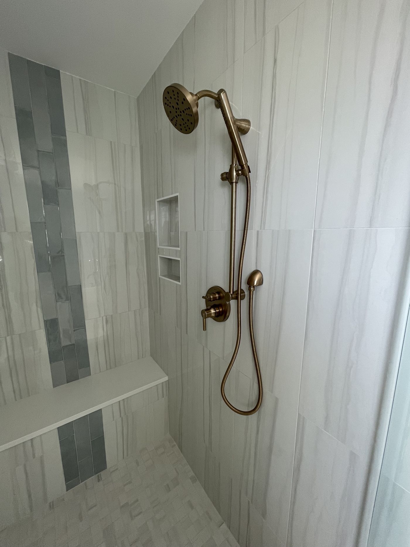 Custom tile shower with rain head and vertical accent stripe — Daybreak Construction