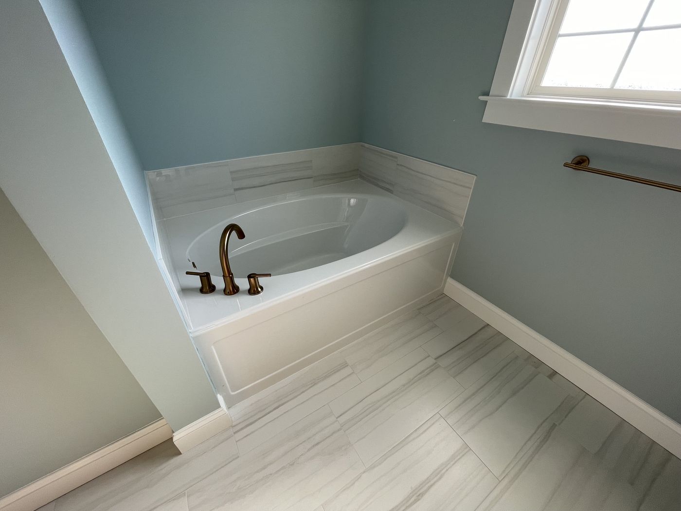 Soaking tub with tile surround and brass fixtures — Daybreak Construction