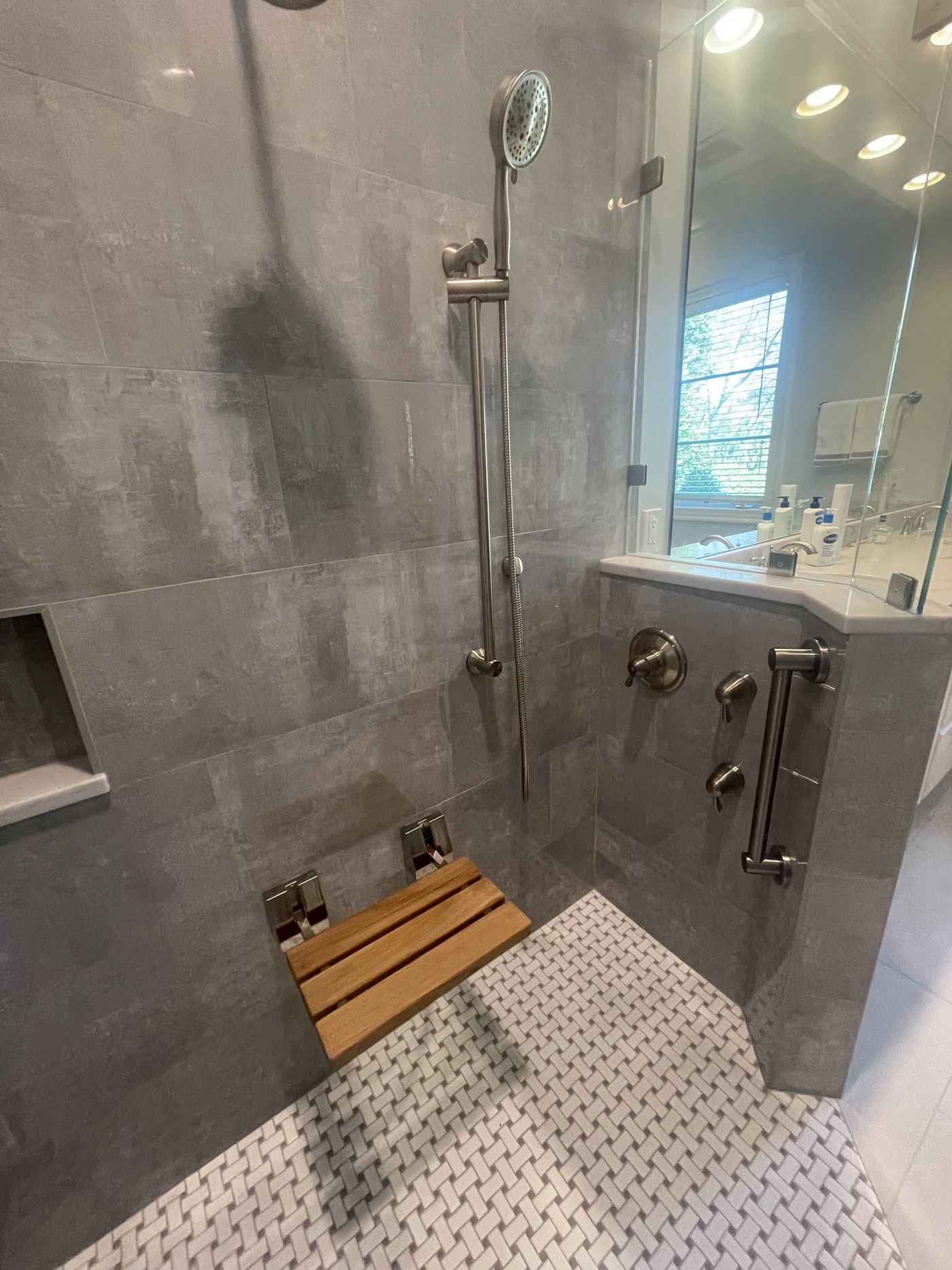 Walk-in shower with teak bench and dual shower heads — Daybreak Construction