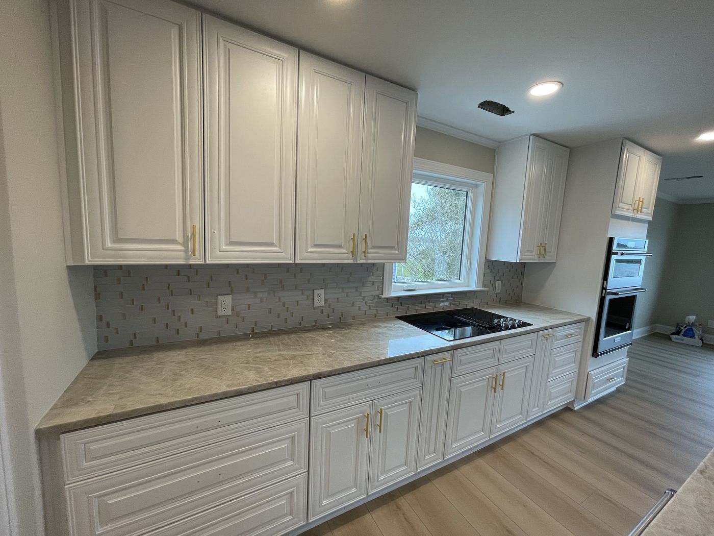 White kitchen cabinetry with tile backsplash and quartz countertops — Daybreak Construction