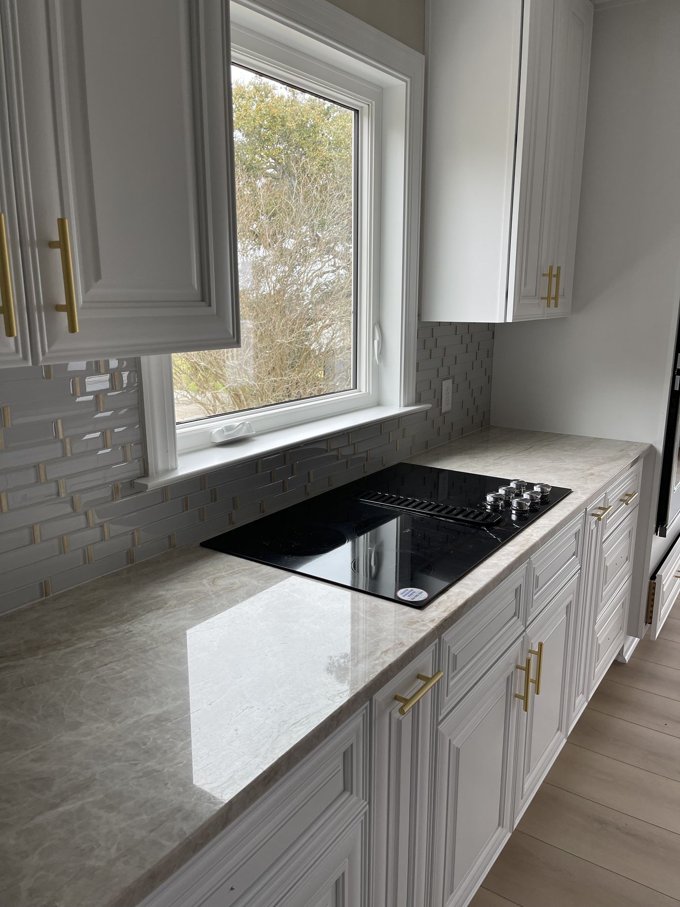 Cooktop with glass-tile backsplash and brass hardware — Daybreak Construction