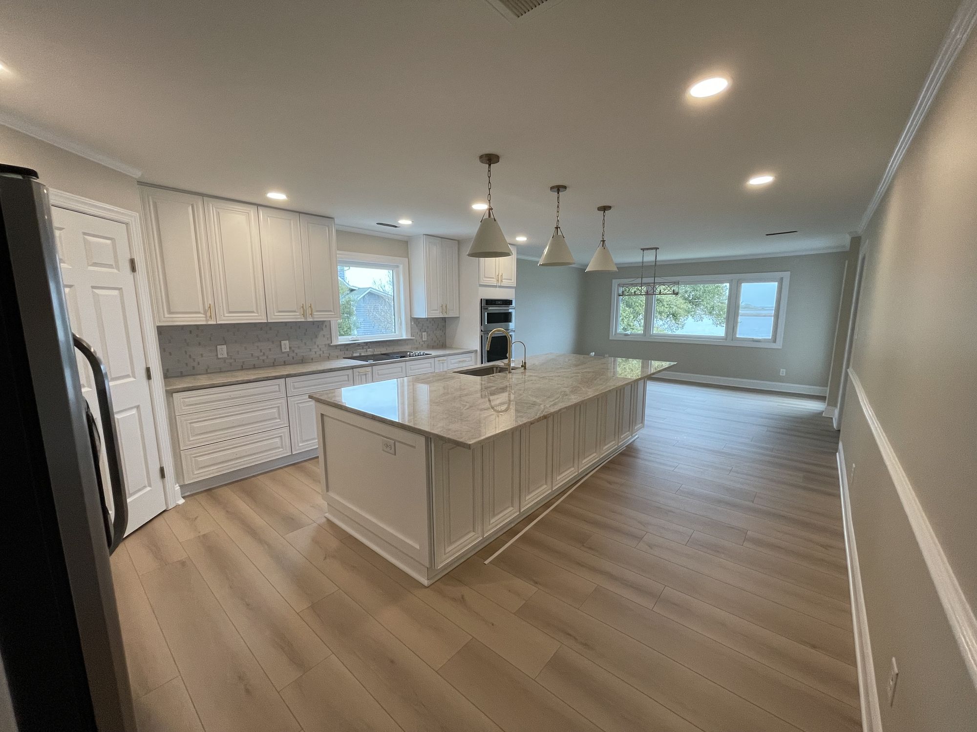 Open-concept kitchen remodel with a large quartz island and white custom cabinetry — Daybreak Construction