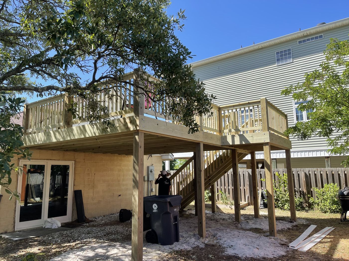 Elevated pressure-treated deck with stairs and under-deck patio — Daybreak Construction
