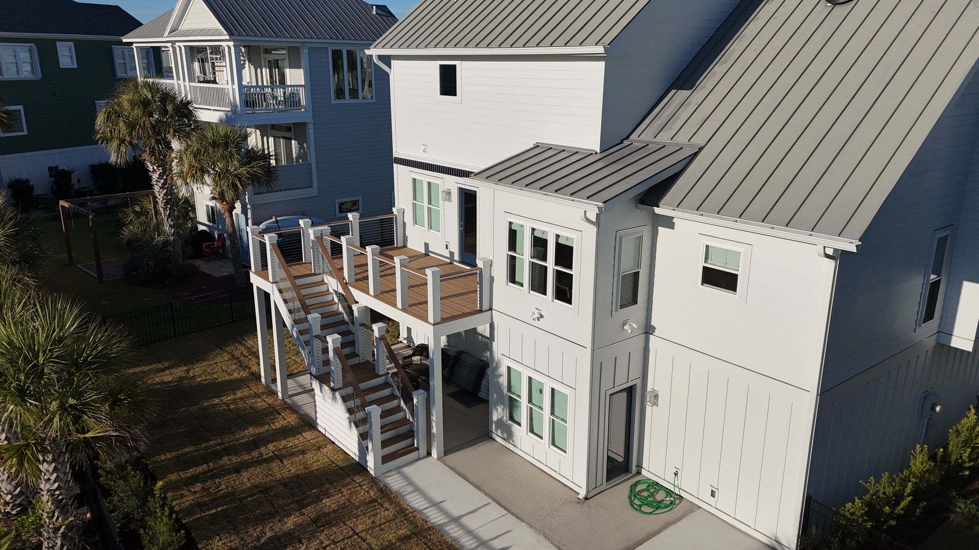 Aerial view of a coastal home with new composite deck and board-and-batten siding — Daybreak Construction